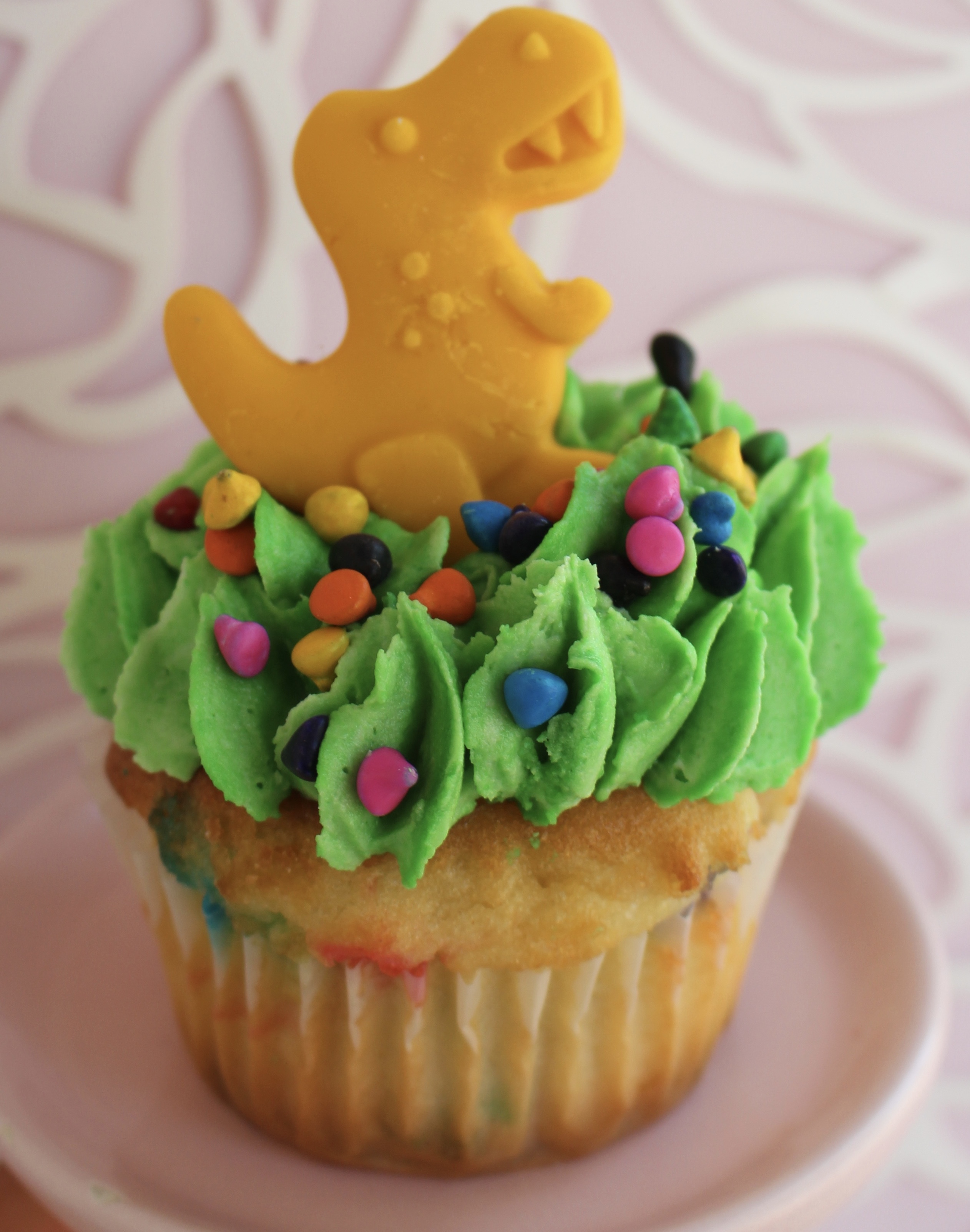 Confetti Cake with vanilla buttercream topping, candies, and a white chocolate dinosaur on top!